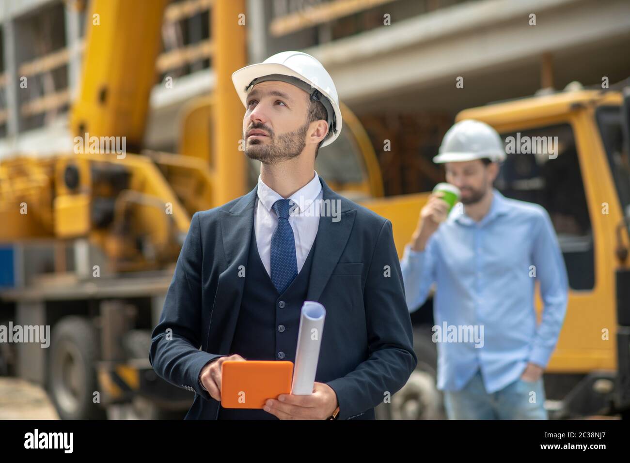 Building site. Building supervisor holding tablet, foreman standing ...