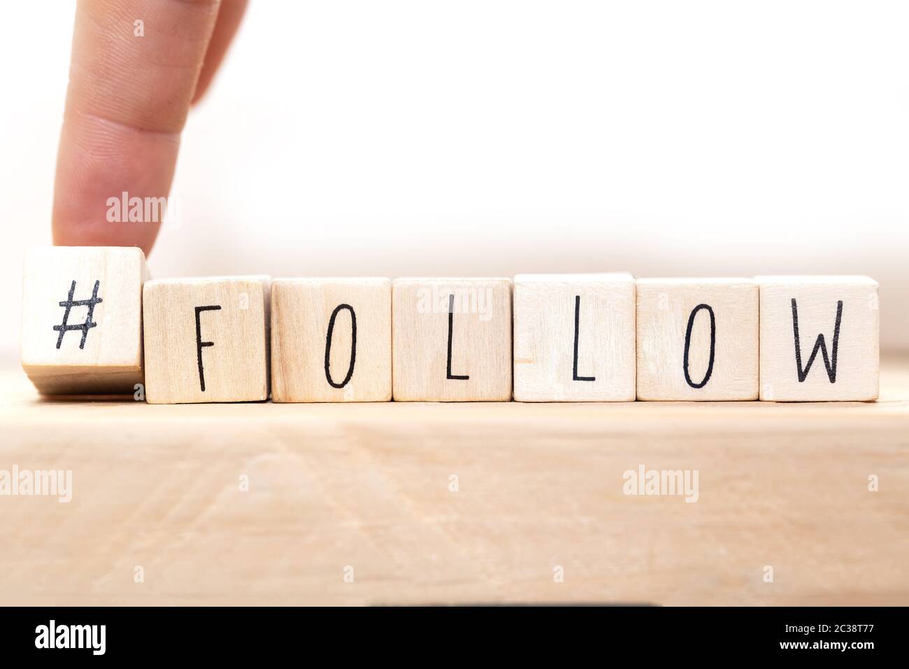 Follow sign made of cubes on a wooden table with Hashtag near white background, socialmedia concept close-up Stock Photo