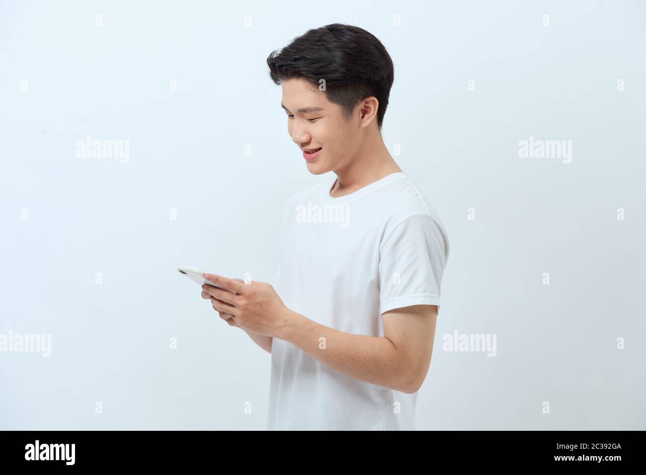 Smiling young good looking Asian man using smartphone to get in touch ...