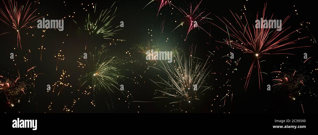 Colorful sparkling fireworks and silver stars on dark night sky. Concept background for new years eve celebrations with space for text. Stock Photo