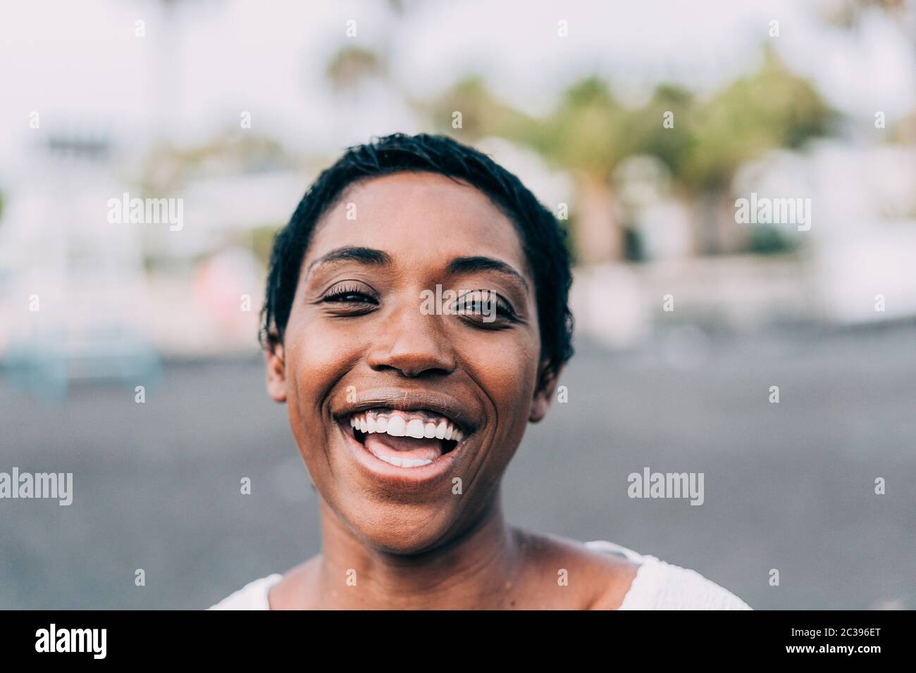 Portrait of african woman outdoor - Happy black female laughing in front of the camera - Real people photography concept - Focus on nose Stock Photo