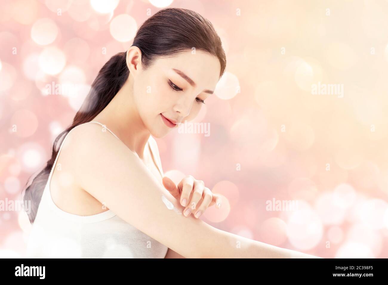 Beautiful young woman applying body lotion Stock Photo - Alamy