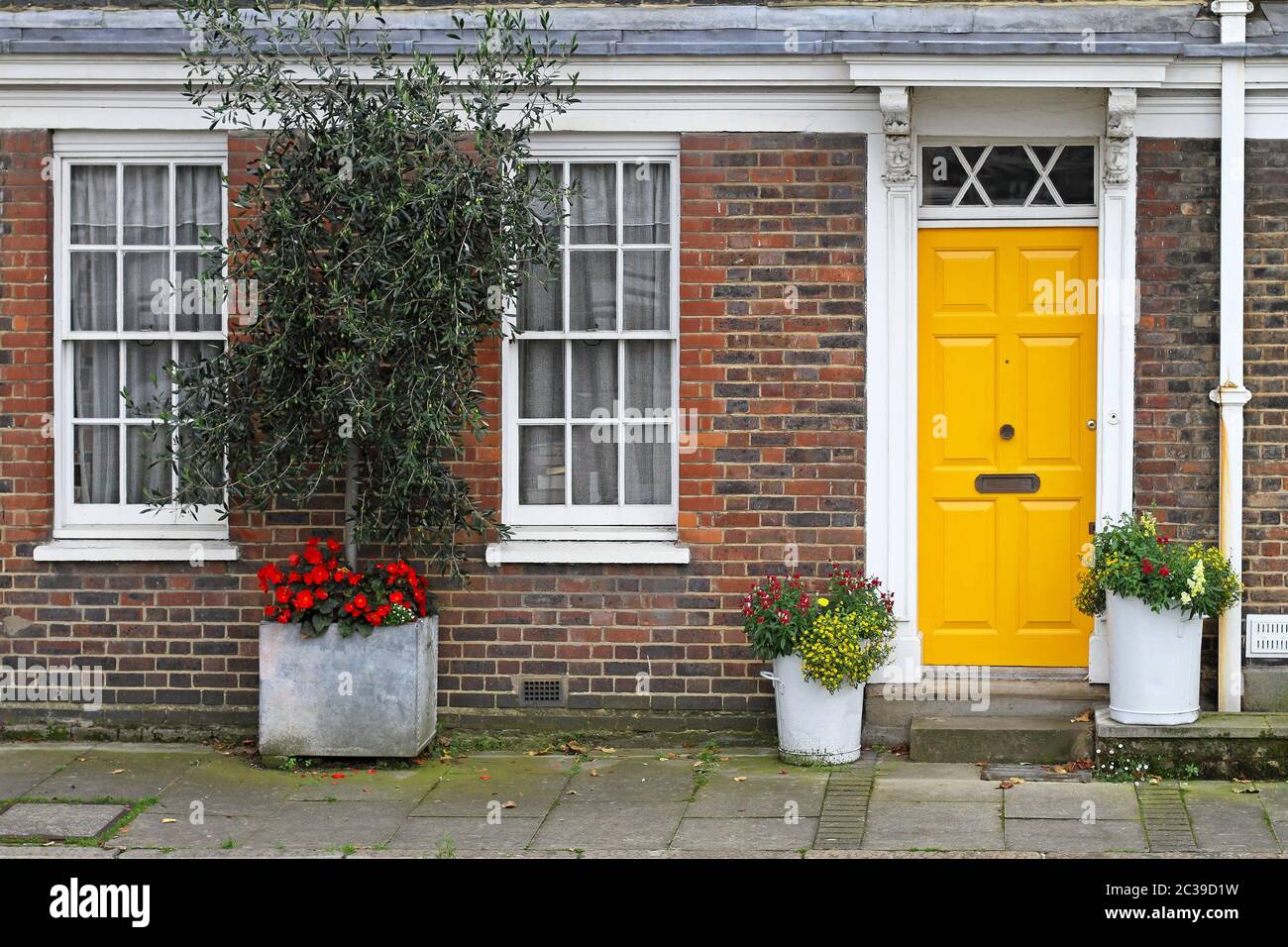 Old english house with brick wall and yellow door hi-res stock ...