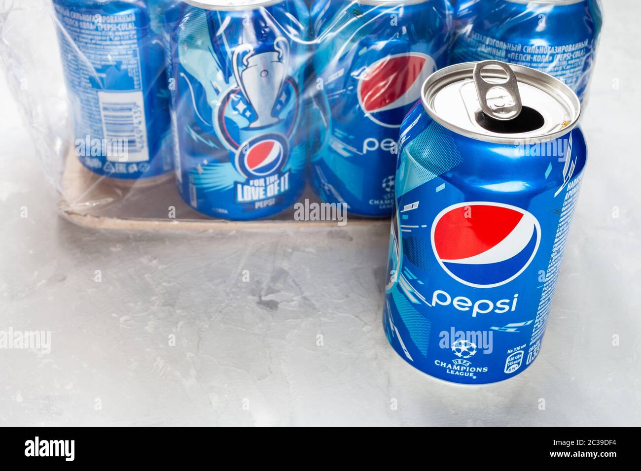 MOSCOW, RUSSIA - JUNE 17, 2020: open can of Pepsi with logo of UEFA Champions League near pack of dozen cans on concrete floor. Pepsi is carbonated so Stock Photo