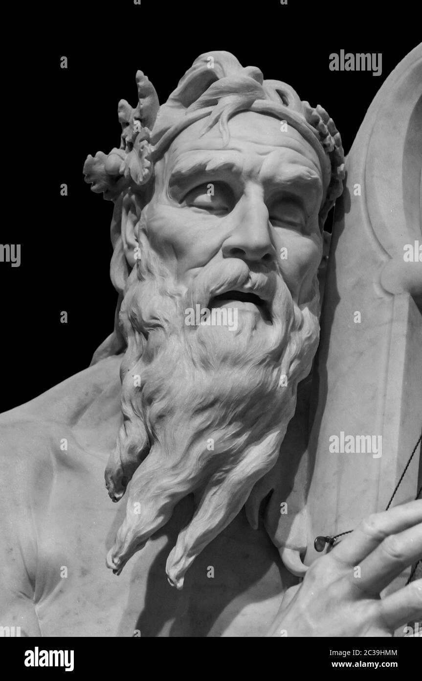Head and shoulders detail of the ancient man with beard sculpture. Antique face with whiskers statue isolated on black backgroun Stock Photo