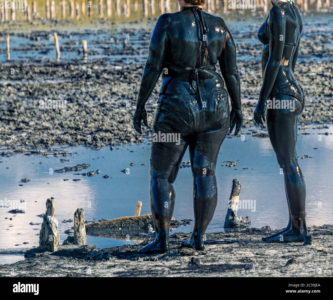 two woman after applying black healing clay. Mud spa on the shore of salt lake. Swimming in the