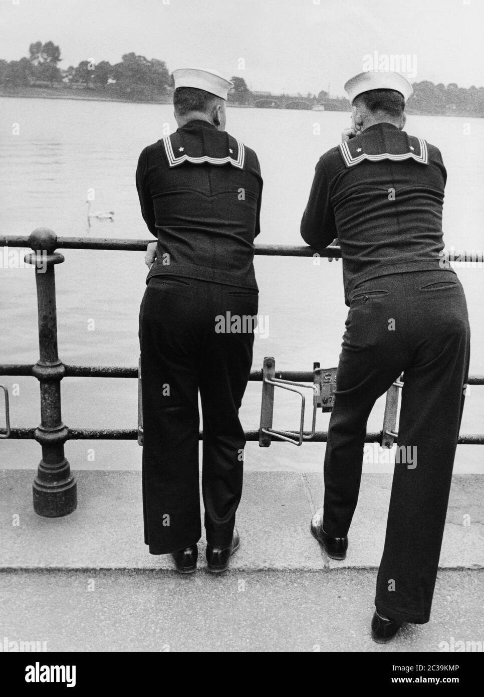 Two US Navy sailors lean against a railing and look across the Binnenalster to the Lombardsbruecke (in the background) during their stay in Hamburg on the occasion of a fleet visit of the US Navy in the 1950s. Stock Photo