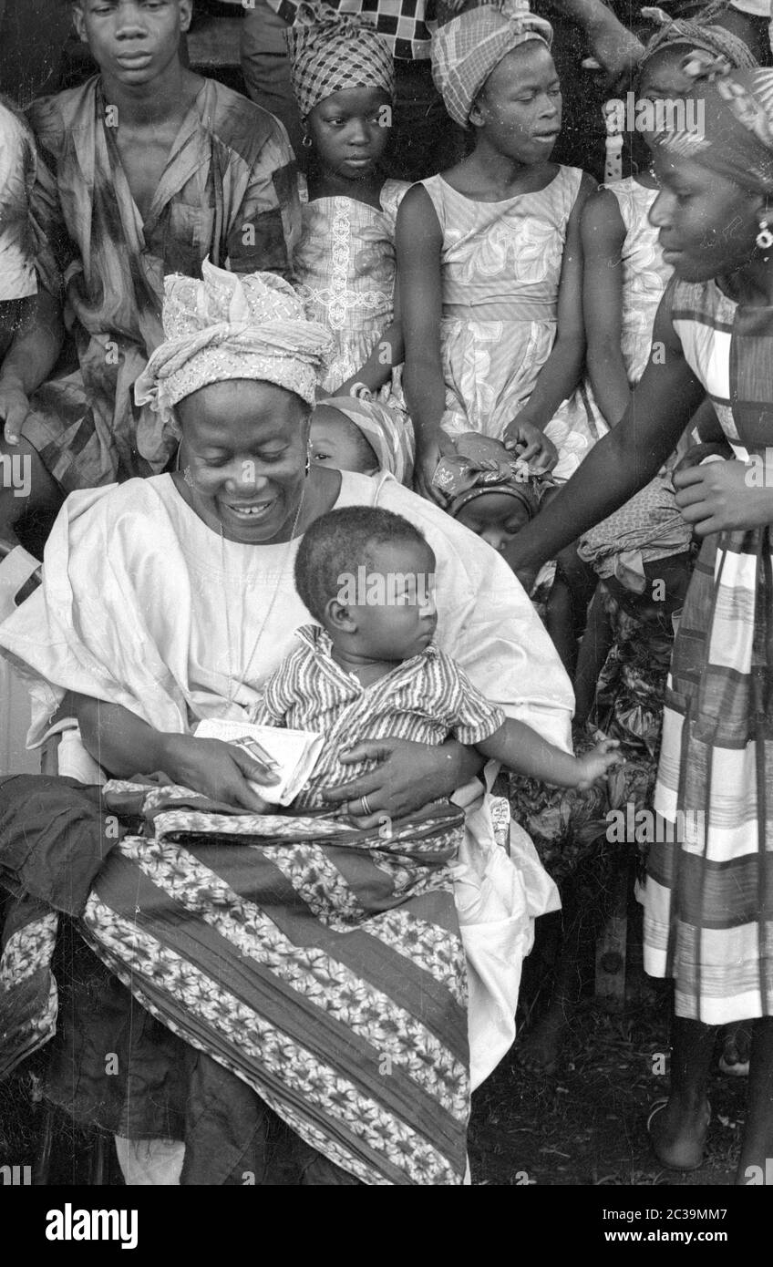 A traditionally dressed mother in Sierra Leone with her baby in a group ...