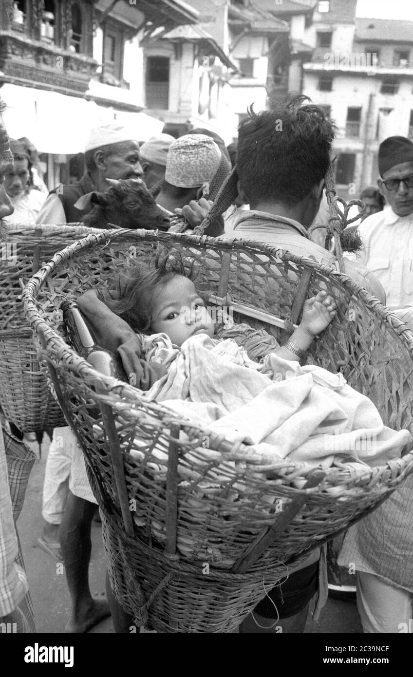 A man carries a small child in a basket on his back in Nepal's capital Kathmandu. Stock Photo