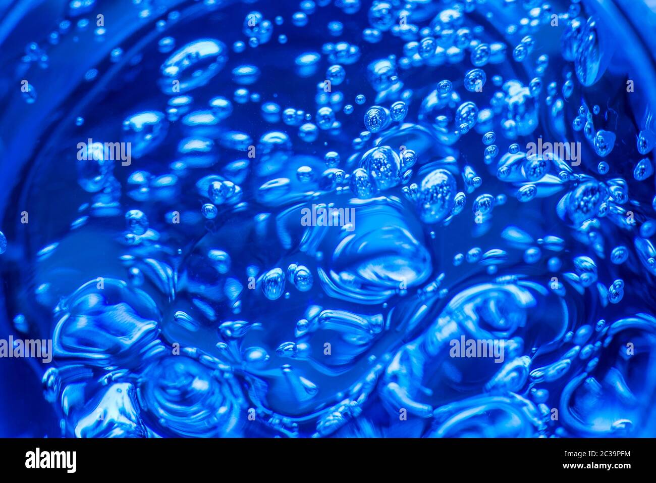 Liquid gel on a digital screen of microscope or sparking water. Bubbles of oxygen in glass of water on a blue background. Minera Stock Photo