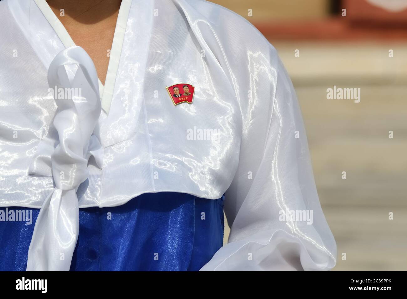 Kaesong, North Korea - May 5, 2019: Close-up of a Kim Il Sung and Kim Jong Il chest badge on the traditional dress hanbok of a North Korean girl membe Stock Photo