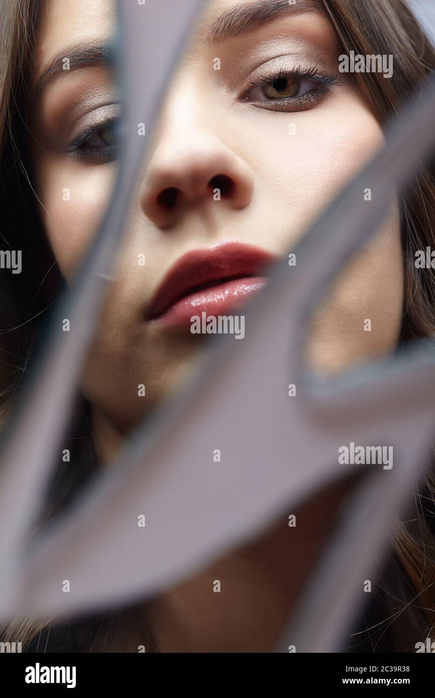 Young woman looks in a broken mirror. Portrait of beautiful female in