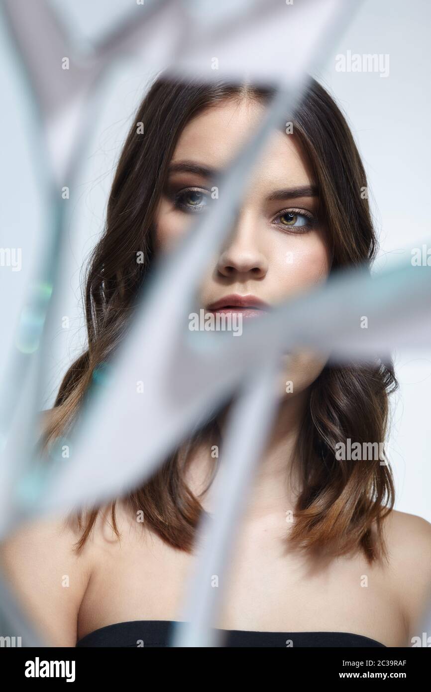 Young woman looks in a broken mirror. Portrait of beautiful female in