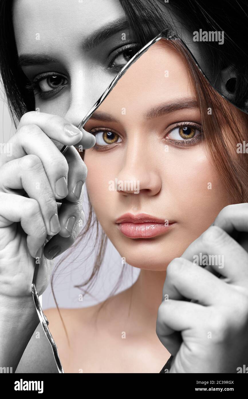 Monochrome portrait of female with mirror shard in hand posing on gray ...