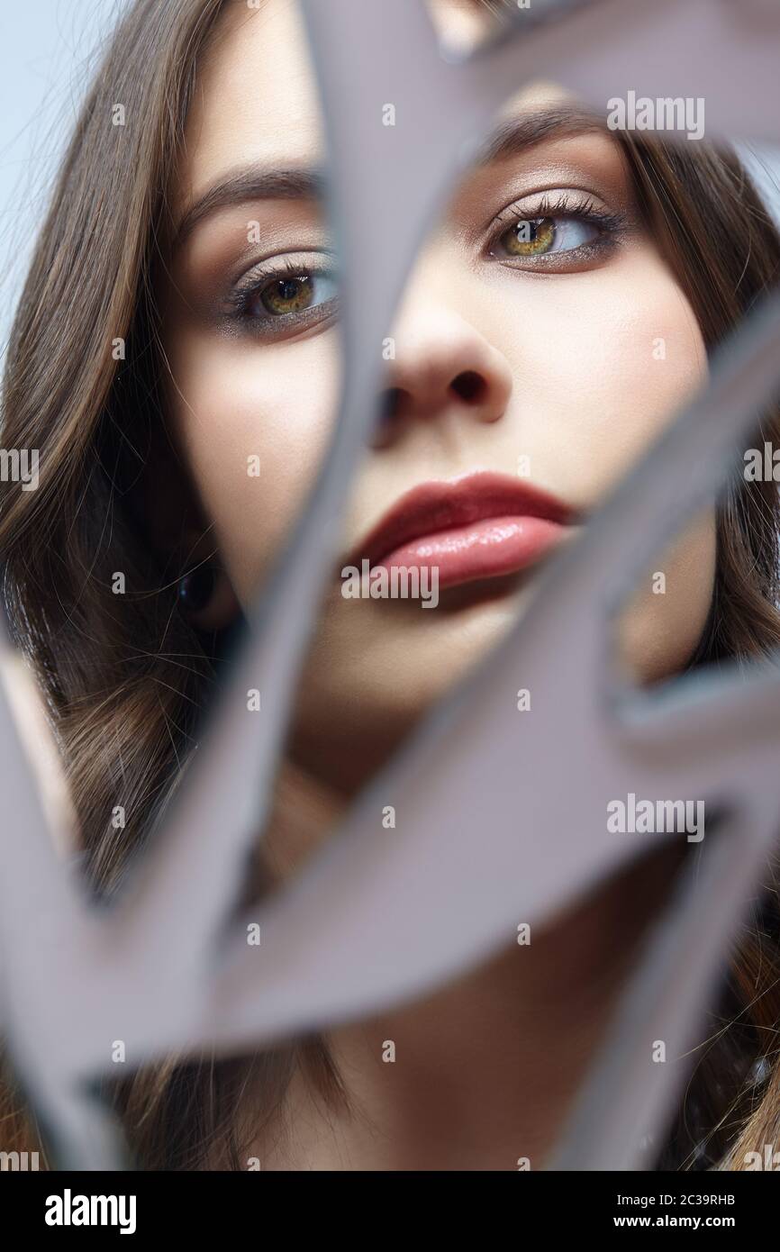 Young woman looks in a broken mirror. Portrait of beautiful female in