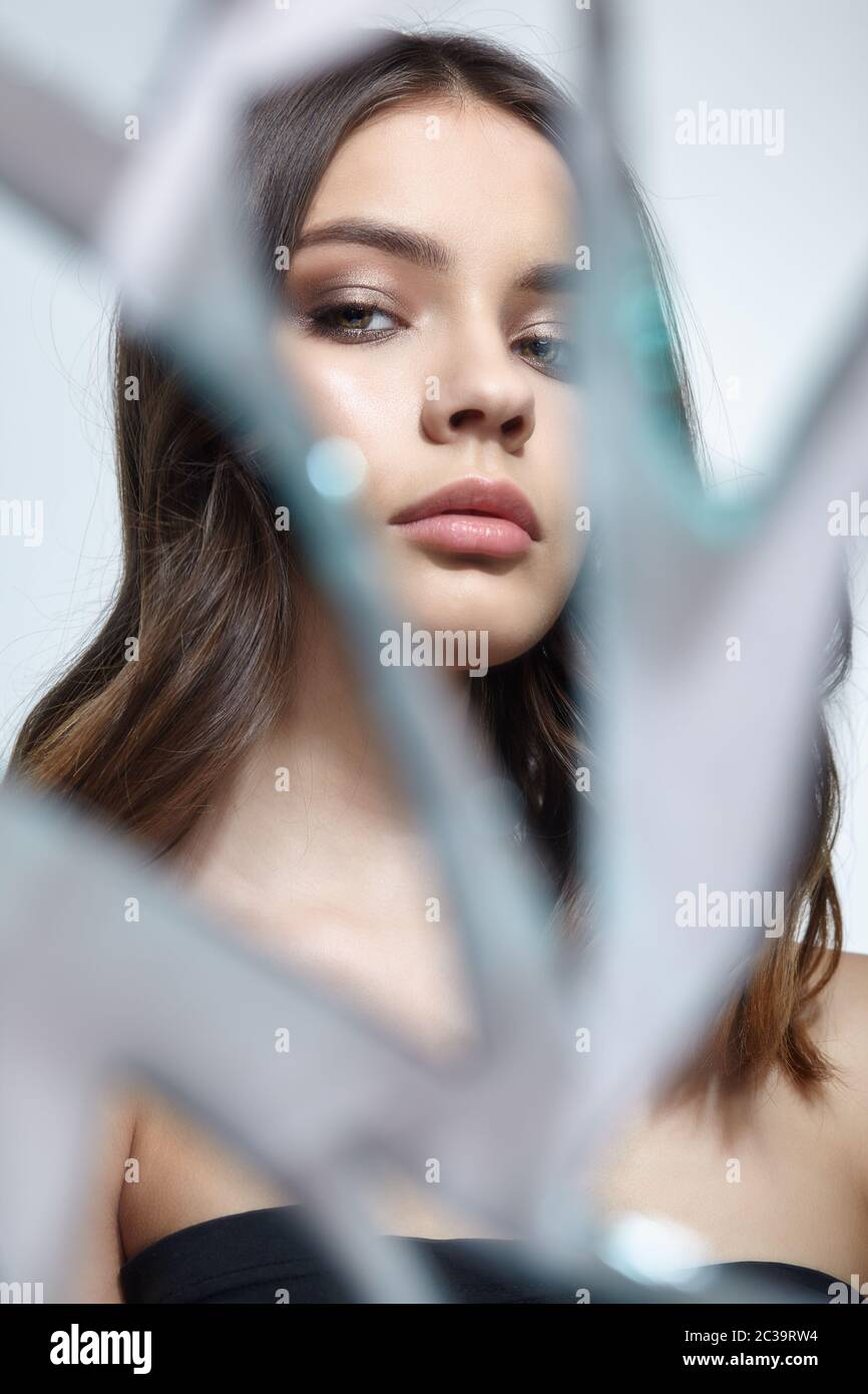 Young woman looks in a broken mirror. Portrait of beautiful female in