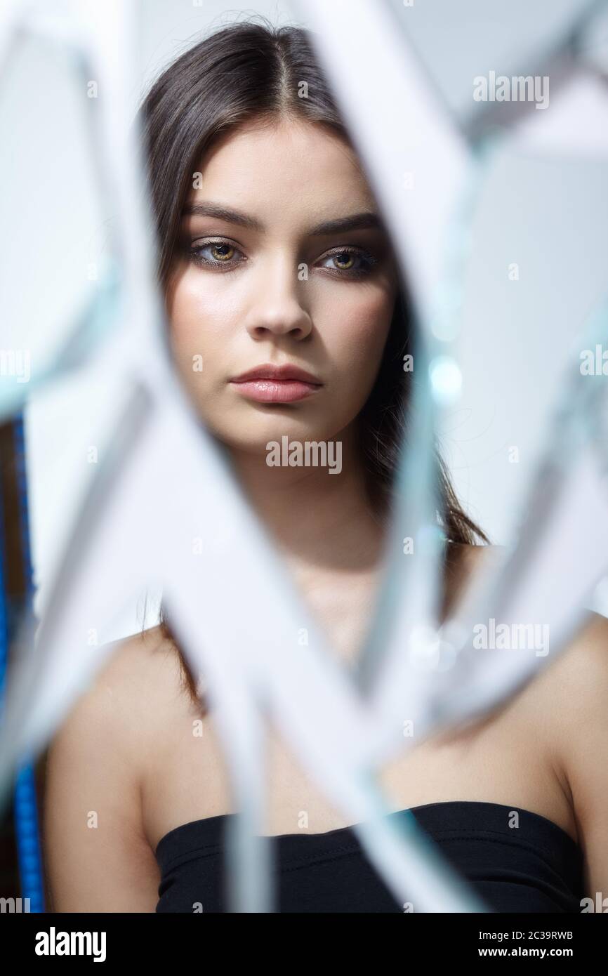 Young woman looks in a broken mirror. Portrait of beautiful female in