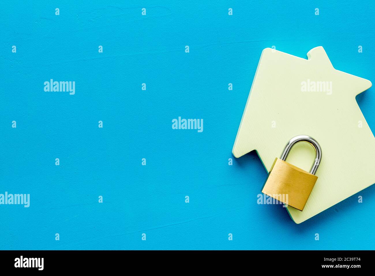 Security concept with lock and house figure on blue table top view copy space Stock Photo
