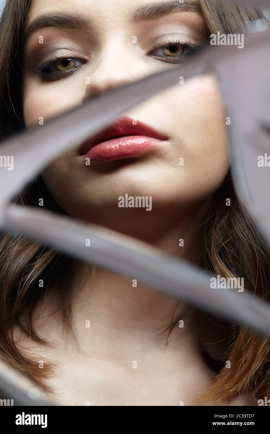 Young woman looks in a broken mirror. Portrait of beautiful female in