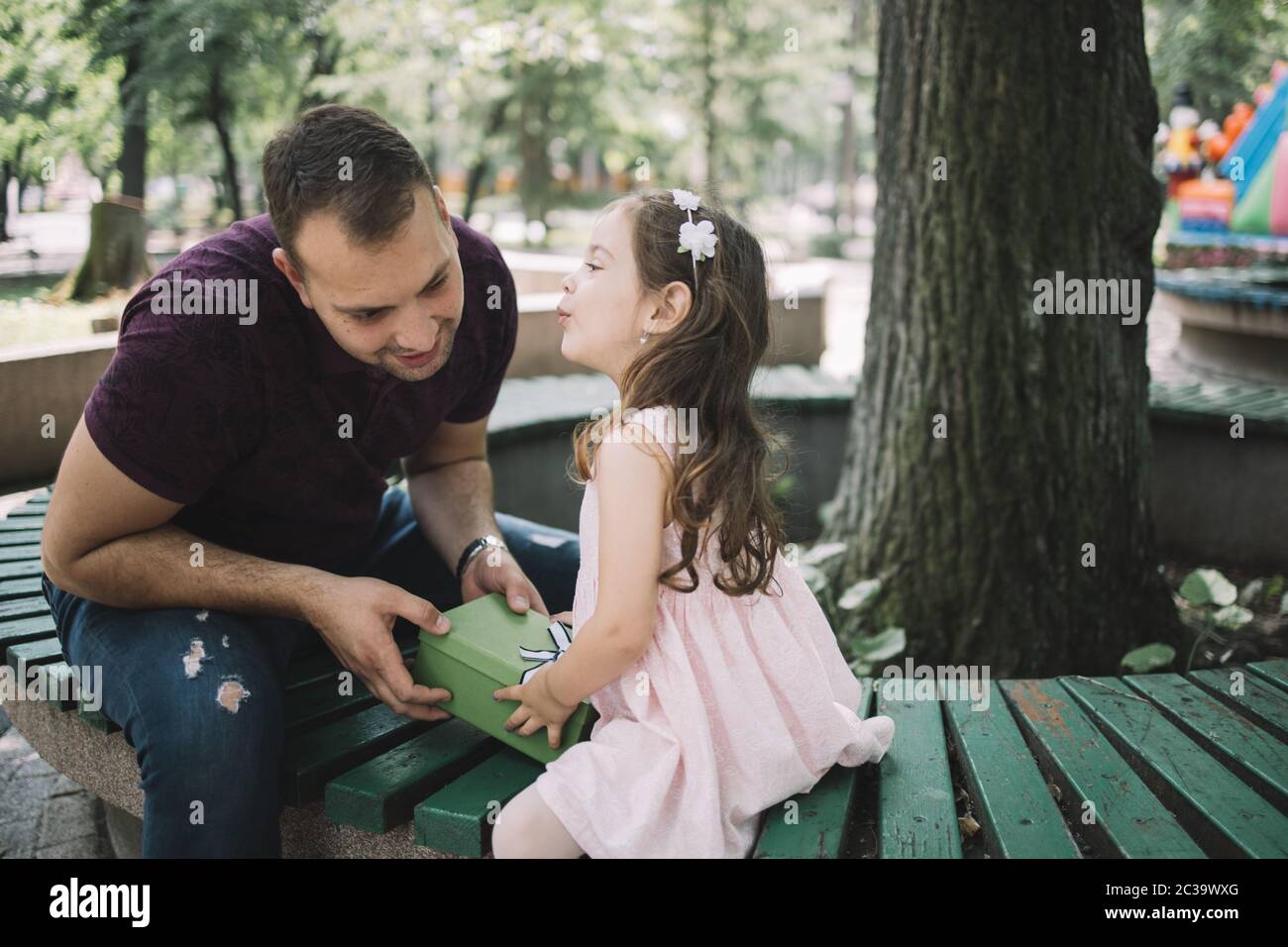 Child kissing man while holding gift box outdoor Stock Photo Alamy