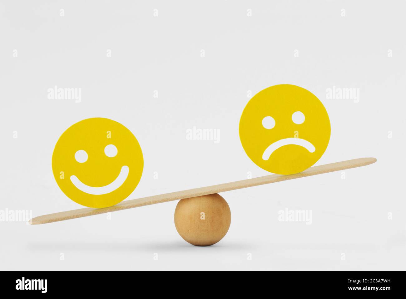 Smiley face and sad face on scale - Concept of happiness as predominant emotion Stock Photo