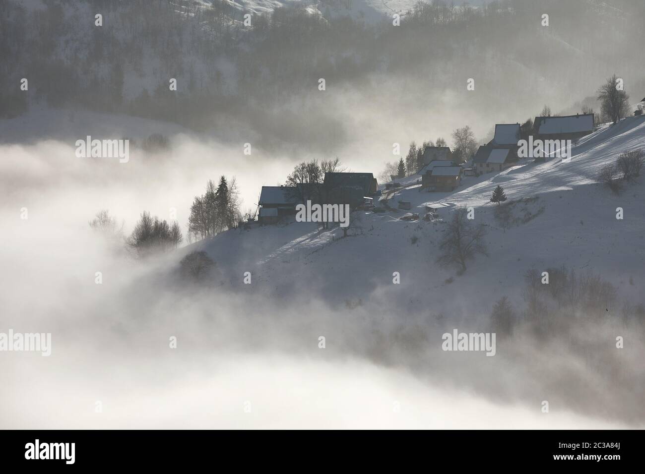 Snowy mountain village in a foggy winter landscape, gloomy weather ...