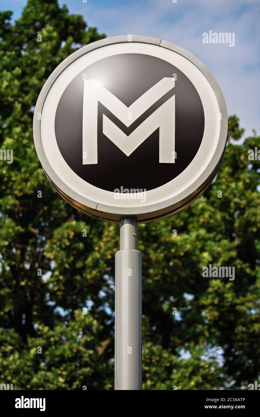 Transportation concept. Sign or symbol of Budapest city metro service located outdoor with trees and sky in the background. Metro sign with trees in t Stock Photo
