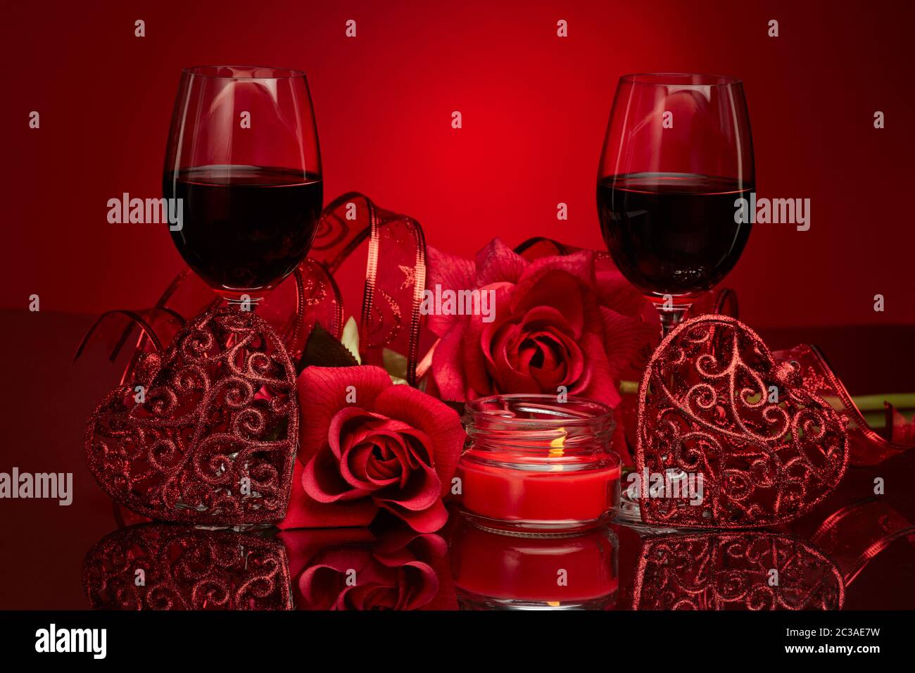 Still life with roses, red hearts and two glasses with wine on red ...