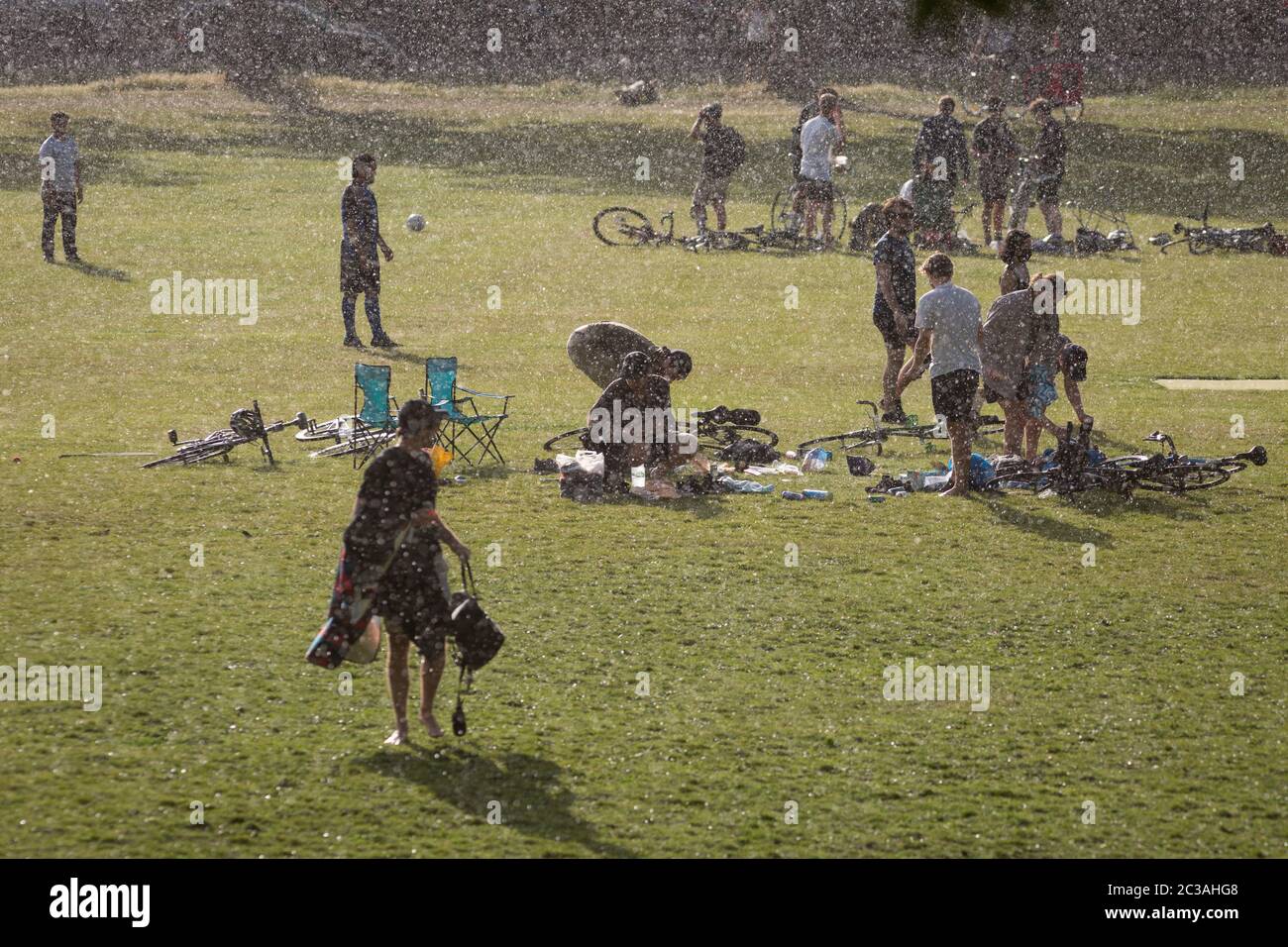 After an afternoon of sunshine and warm temperatures during the continuing UK Coronavirus lockdown, a sudden and torrential downpour of rain catches park users by surprise, in Ruskin Park, a public green space in Lambeth, on 14th June 2020, in London, England. The current UK Covid-19 death toll now stands at 41,662, an increase over the last 24 hours of 181, although Prime Minister Boris Johnson is coming under pressure to review the case for a reduction of the 2 metre social distance rule, due to its effect on jobs and wider economy. Stock Photo