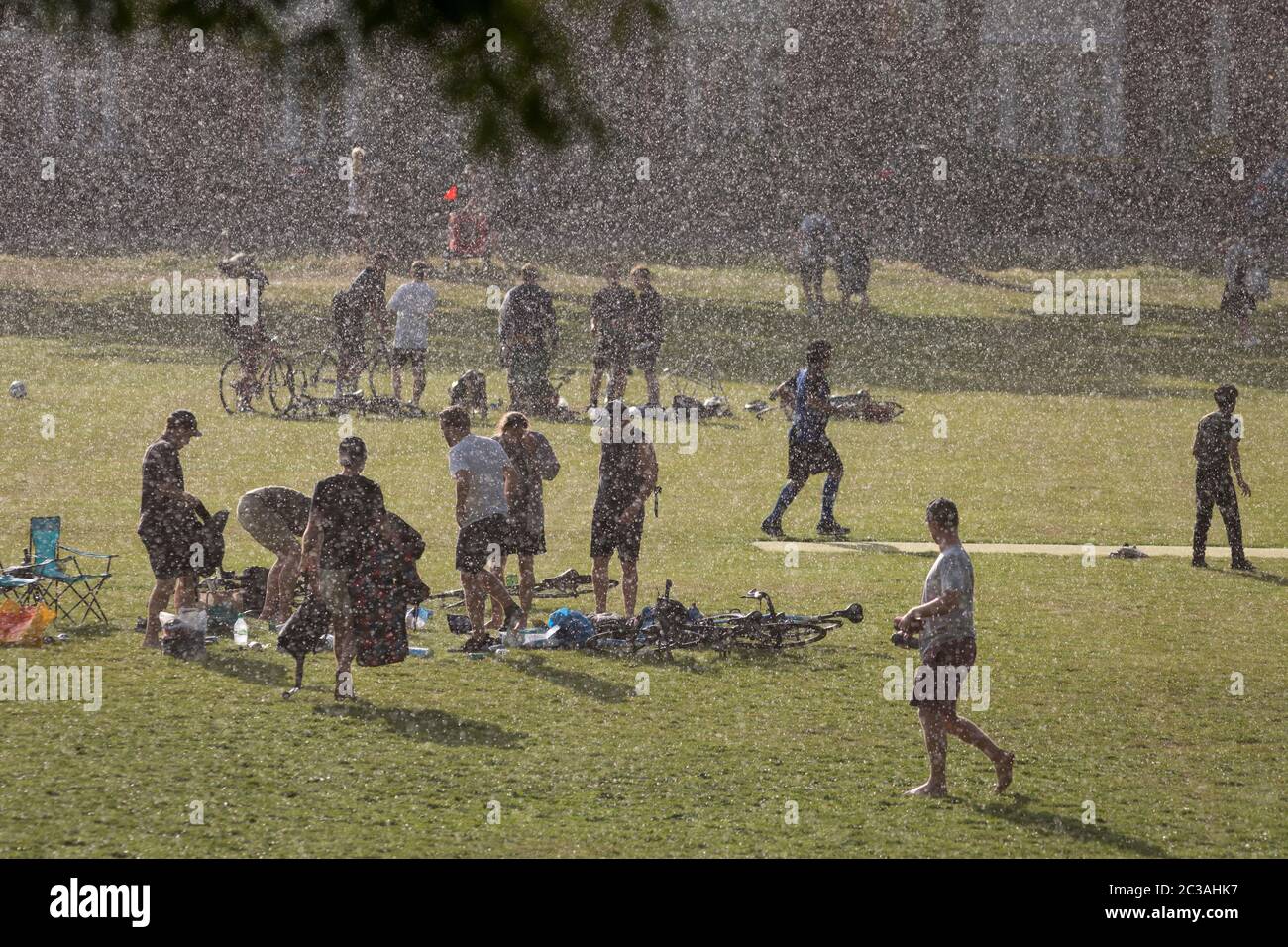 After an afternoon of sunshine and warm temperatures during the continuing UK Coronavirus lockdown, a sudden and torrential downpour of rain catches park users by surprise, in Ruskin Park, a public green space in Lambeth, on 14th June 2020, in London, England. The current UK Covid-19 death toll now stands at 41,662, an increase over the last 24 hours of 181, although Prime Minister Boris Johnson is coming under pressure to review the case for a reduction of the 2 metre social distance rule, due to its effect on jobs and wider economy. Stock Photo