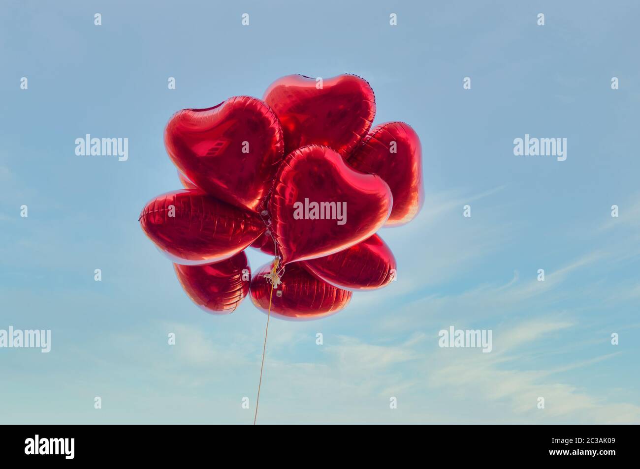 Group of heart shaped red air baloon on blue sky with clouds. Valentine's day and romance concept. Stock Photo