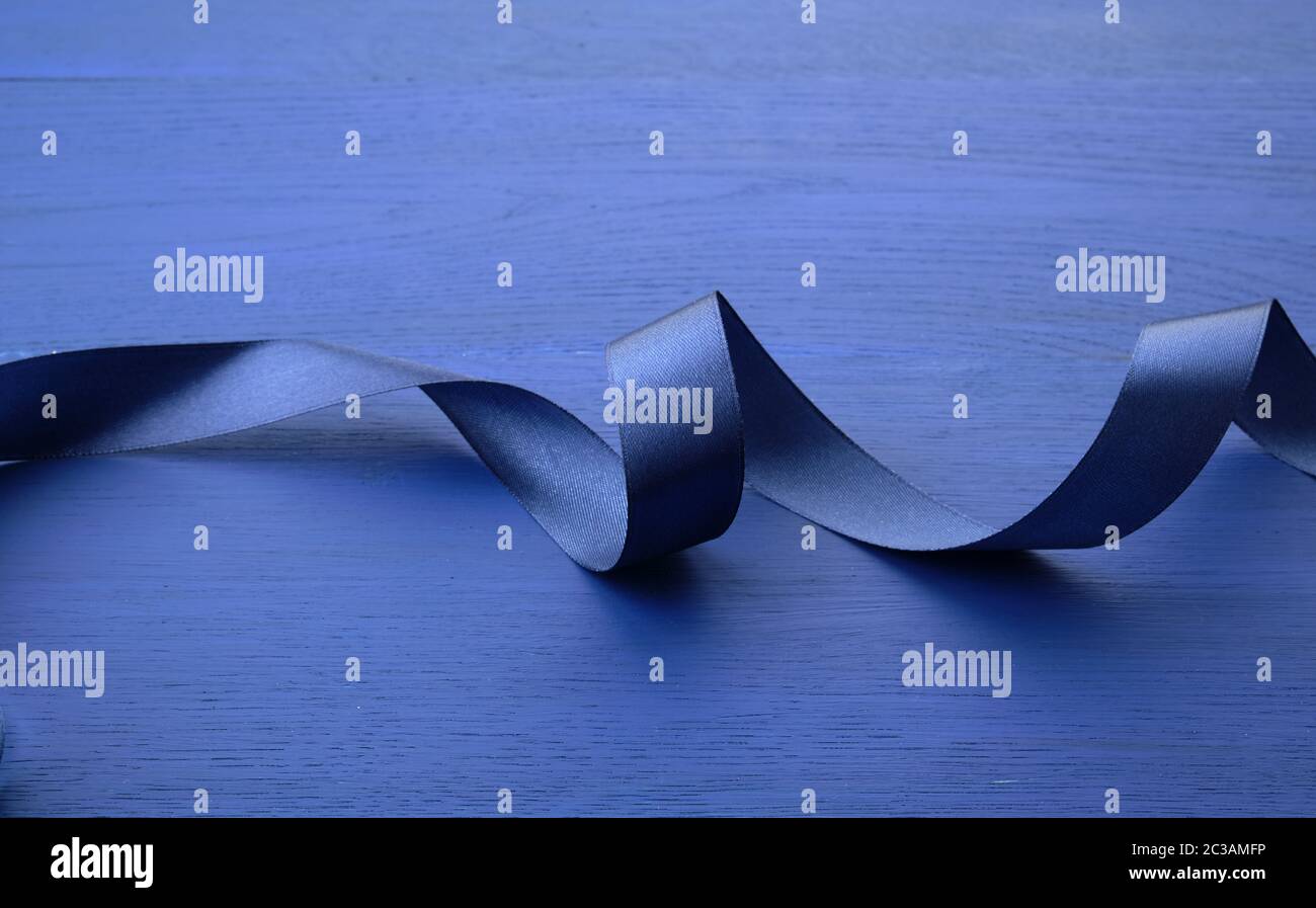 Twisted Ribbons Blue blue silk thin ribbon twisted on a blue wooden background, trendy ...