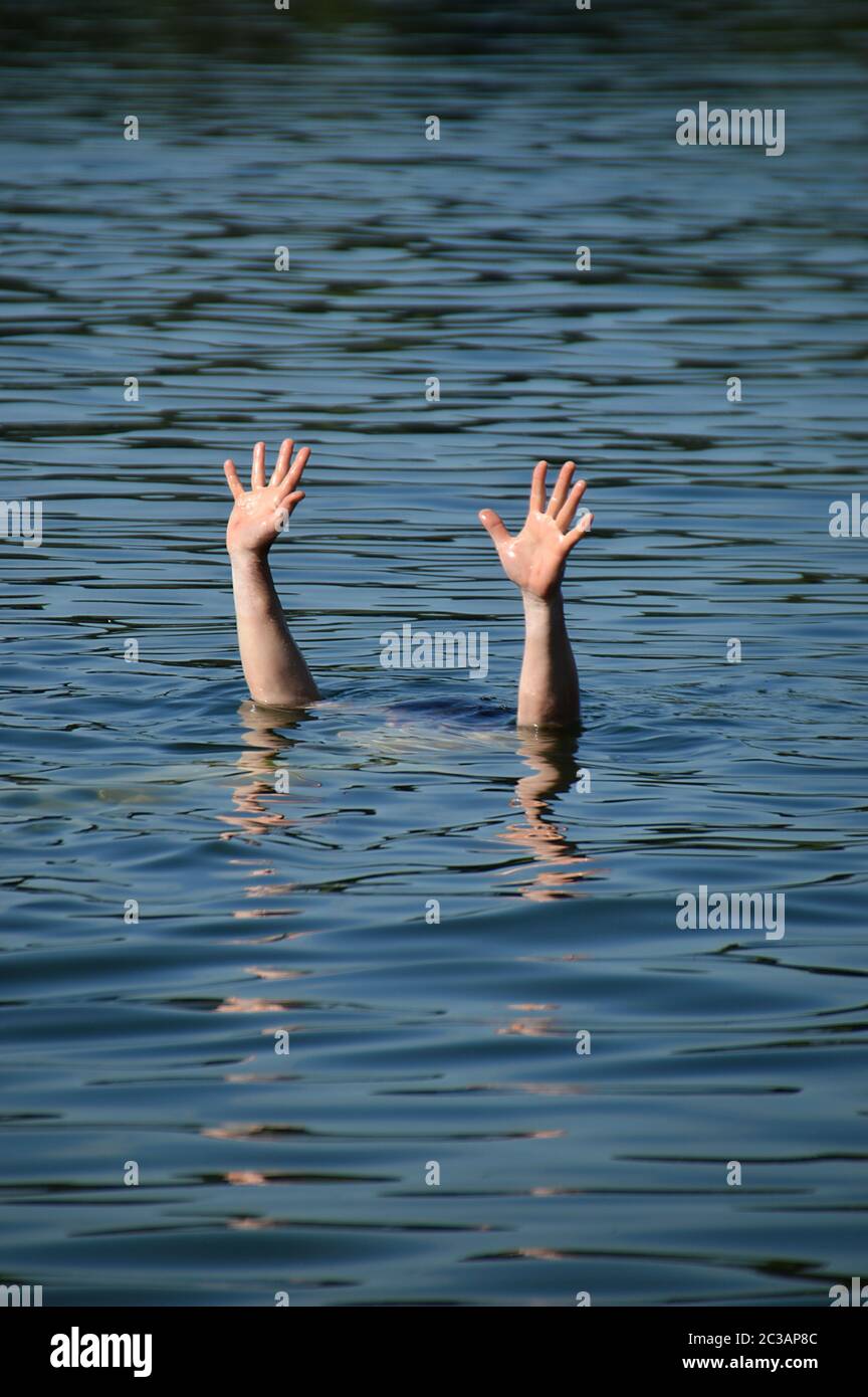 hands of a drowning person raised out of the water for help Stock Photo