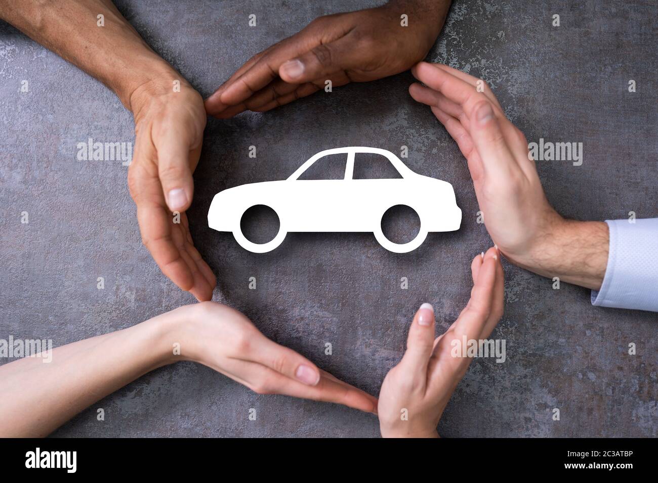People Hands Protecting Cutout Car Shape At Desk Stock Photo