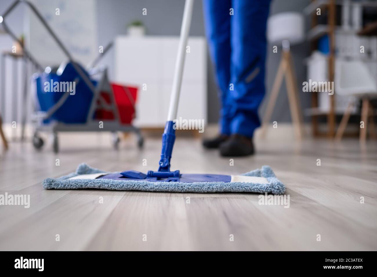 Happy Young Man Cleaning The Floor With Mop In Modern Office Stock Photo