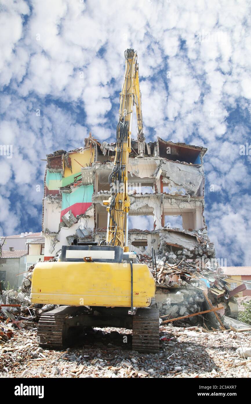 High reach demolition excavator working demolition site. Construction machinery demolishing building. Stock Photo