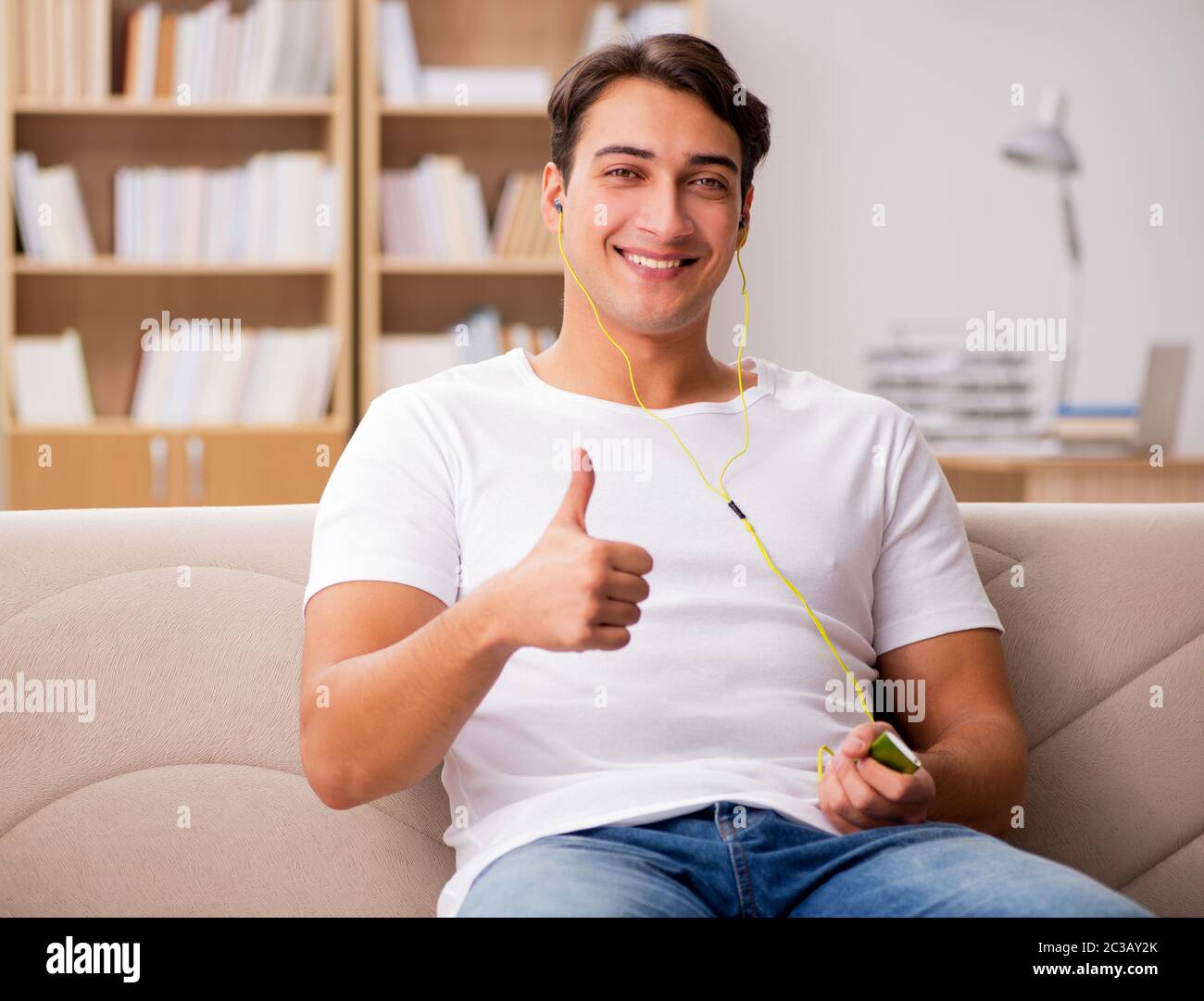 Man listening music sitting in couch Stock Photo - Alamy