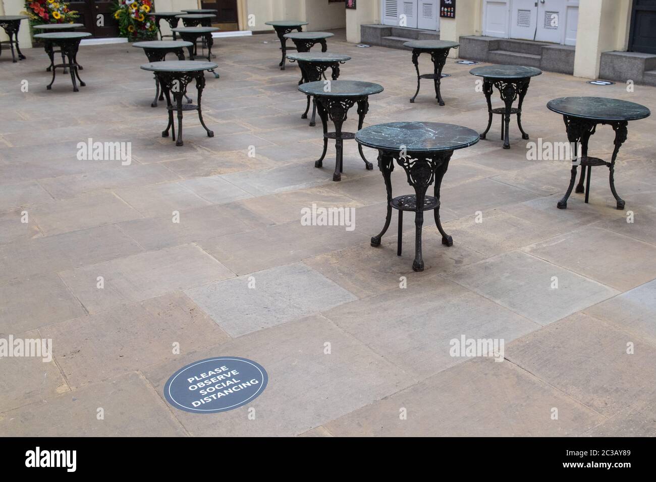 Empty tables alongside a social distancing sign in Covent Garden market, London, as further coronavirus lockdown restrictions are lifted in England. Stock Photo