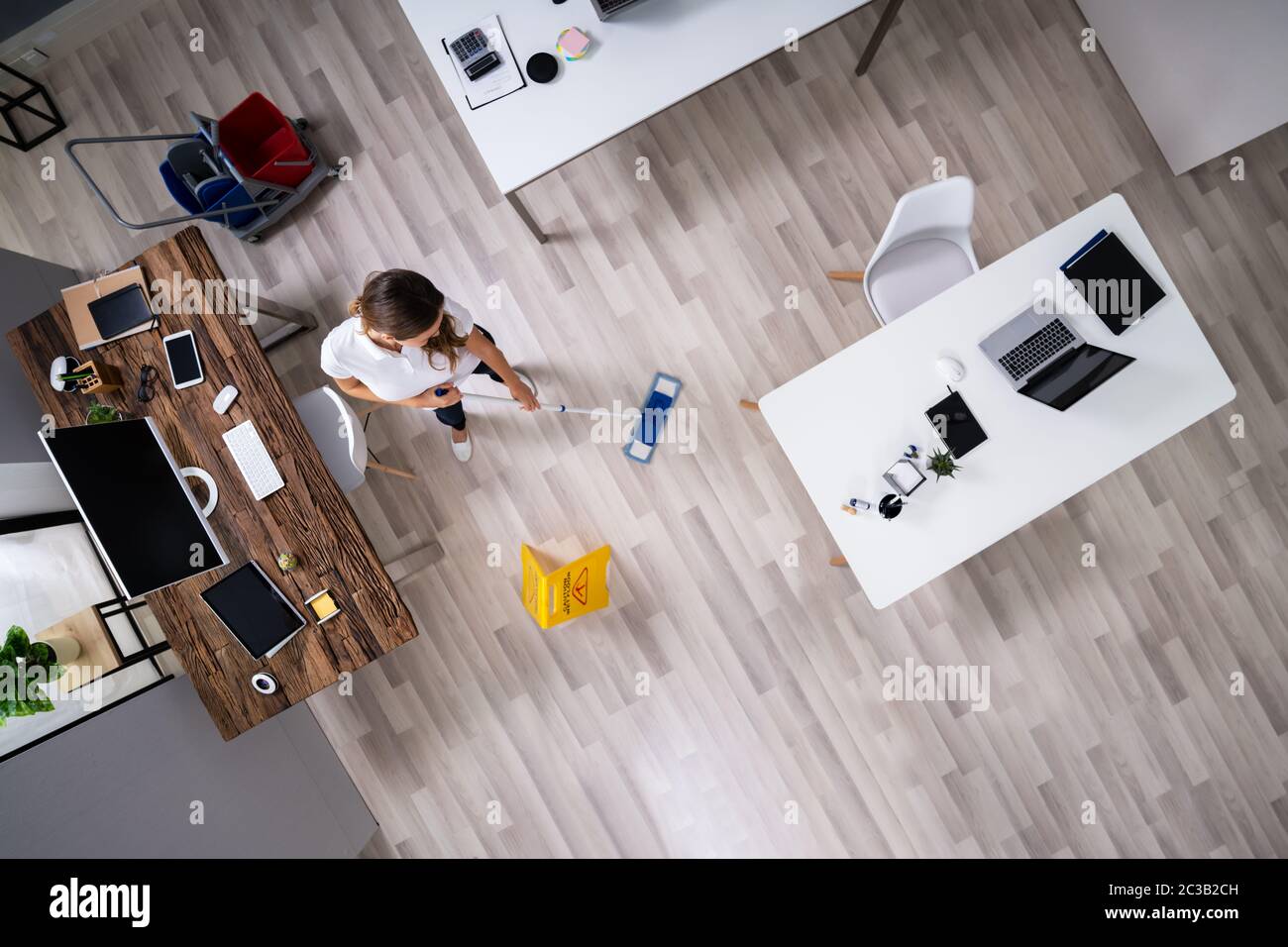 Full Length Of Female Janitor Mopping Floor In Office Stock Photo