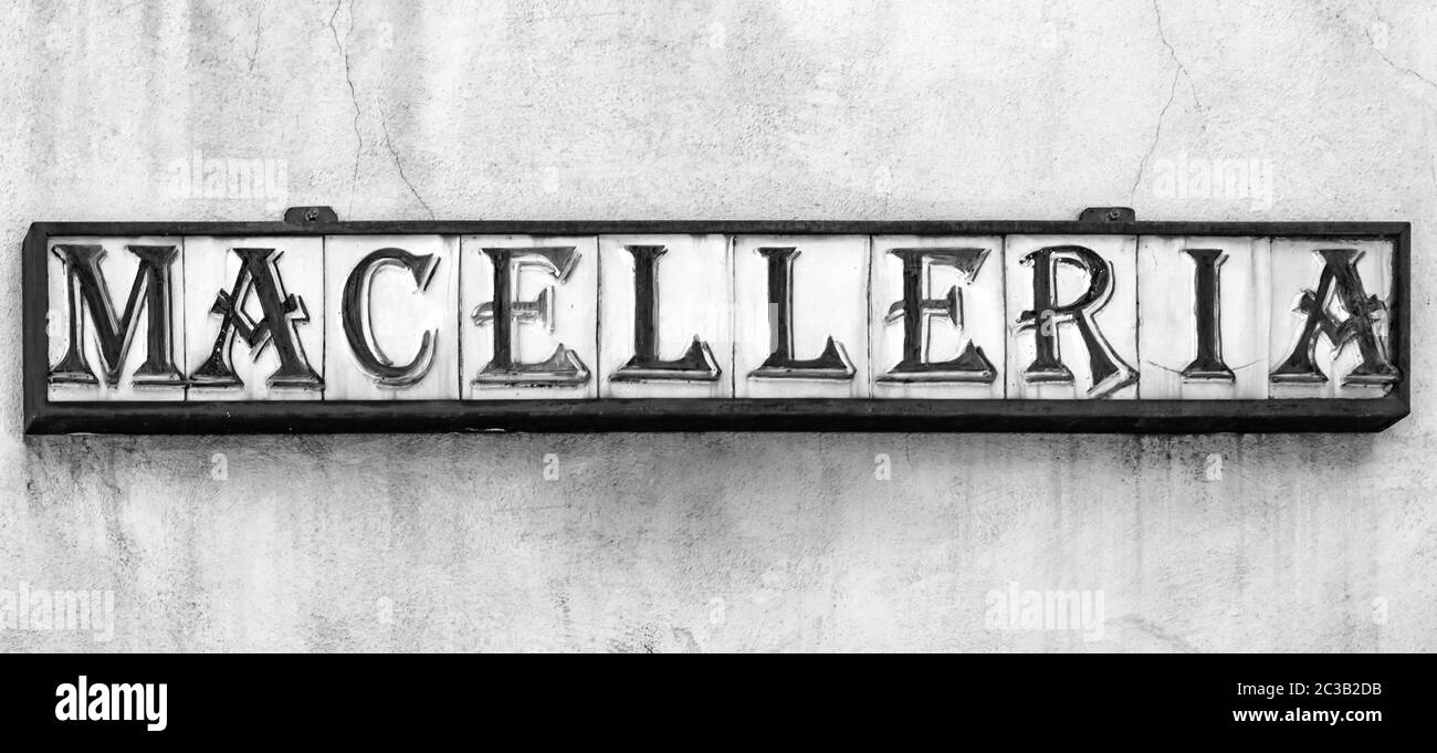 An ancient craft sign of an Italian butcher shop. Ceramic tiles inserted in a metal structure, compose the word 'MACELLERIA', in algerian font, a vint Stock Photo