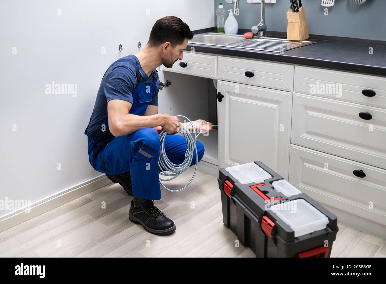 Male Plumber Cleaning Clogged Sink Pipe In Kitchen Stock Photo - Alamy