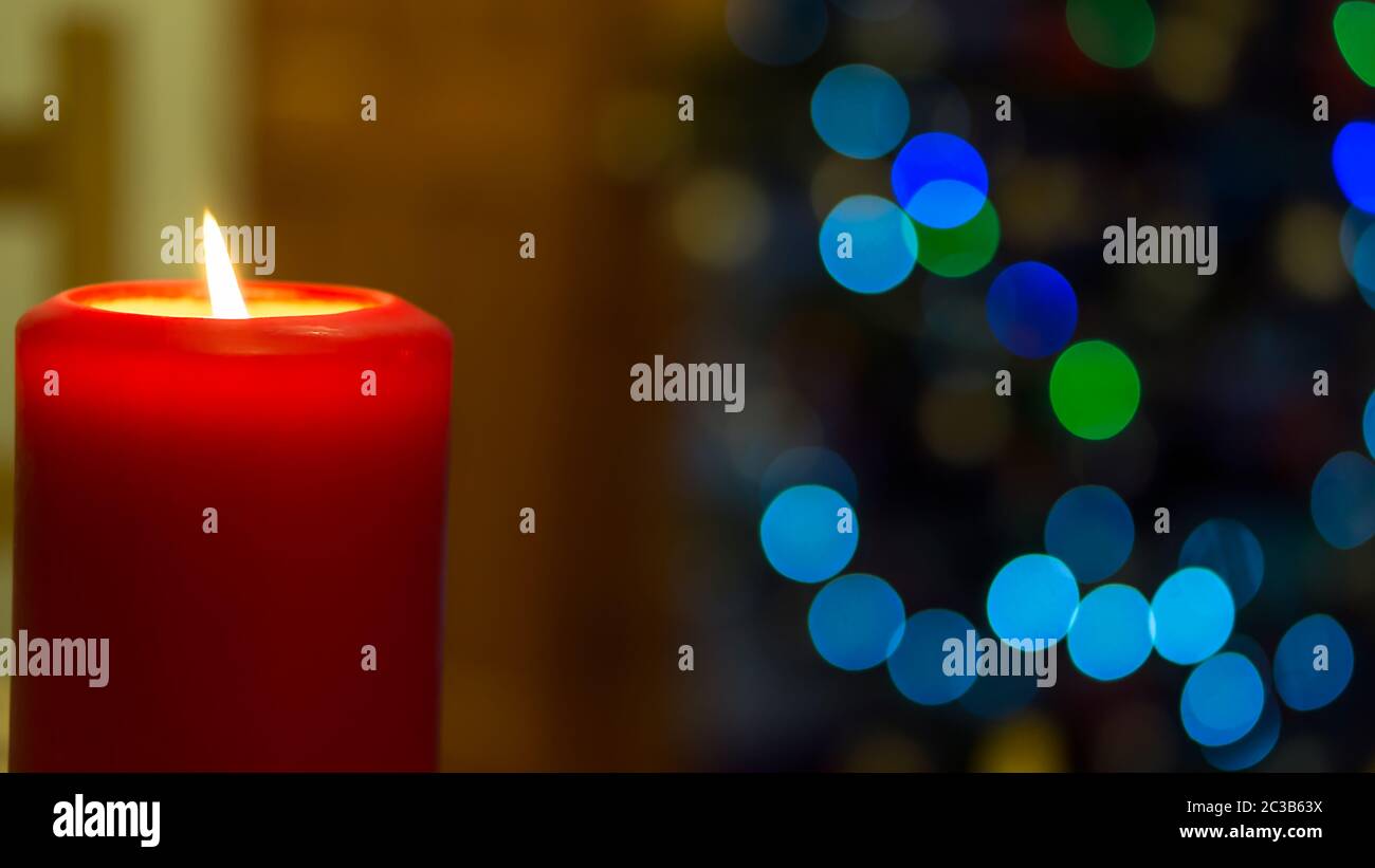 Large red burning candle on blurred background with bokeh Stock Photo