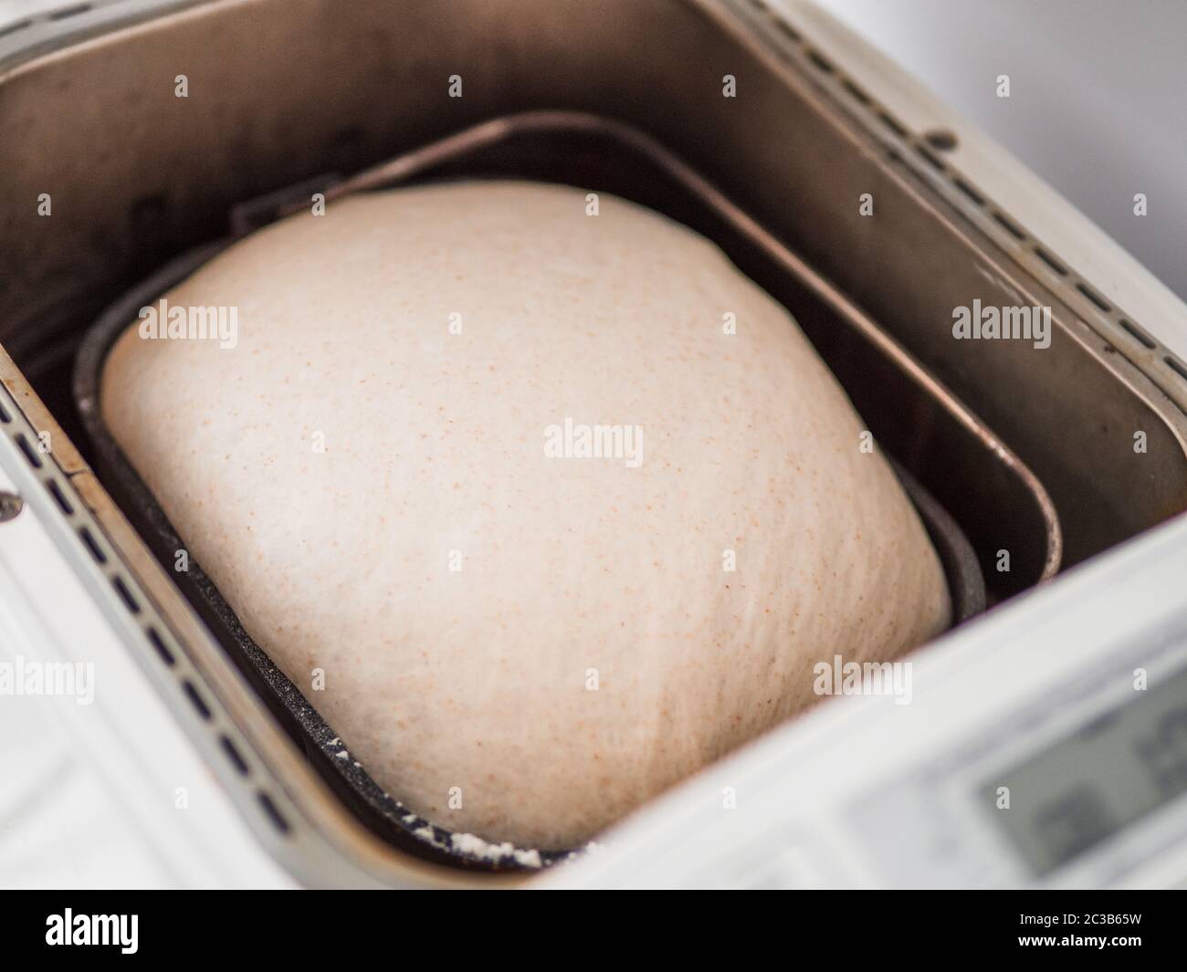 Dough in bread pan of autimatic breadmaker for home use. Perfect raised dough ready for baking in smart bread maker machine with digital display Stock Photo