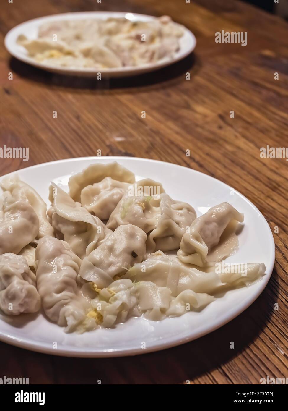 Plates of ready freshly cooked dumplings made during chinese dumpling making and cooking class in a travelers hostel, Chengdu, Sichuan Province, China Stock Photo