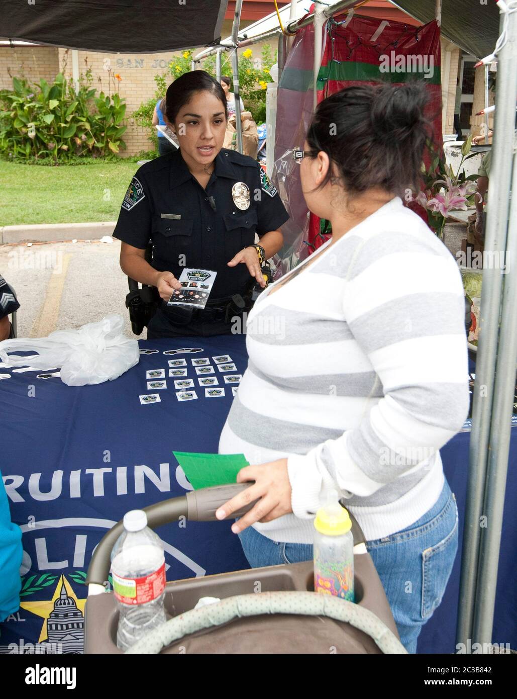 Austin, Texas USA, October 6, 2012: Female Hispanic police officer talks to visitors at a recruiting booth for the Austin Police Department during a church festival. ©MKC / Daemmrich Photos Stock Photo