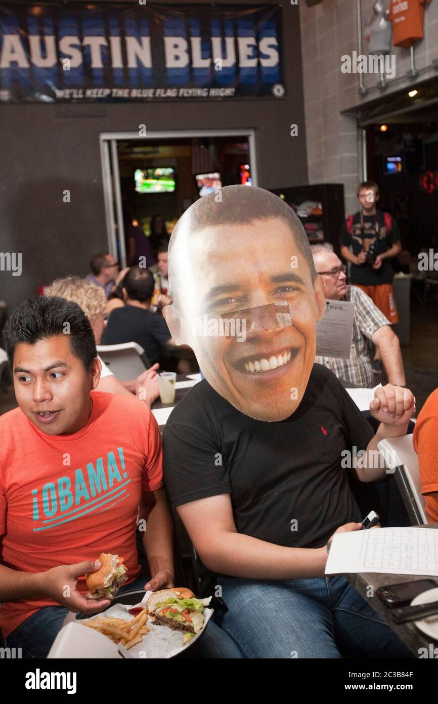 Austin, Texas USA, October 3, 2012: Large group attends a watch party for the first Mitt Romney/Barack Obama presidential debate on TV from a restaurant close to the University of Teas campus. This Obama supporter is wearing a 'fathead' poster of Pres. Obama's face. ©MKC / Daemmrich Photos Stock Photo