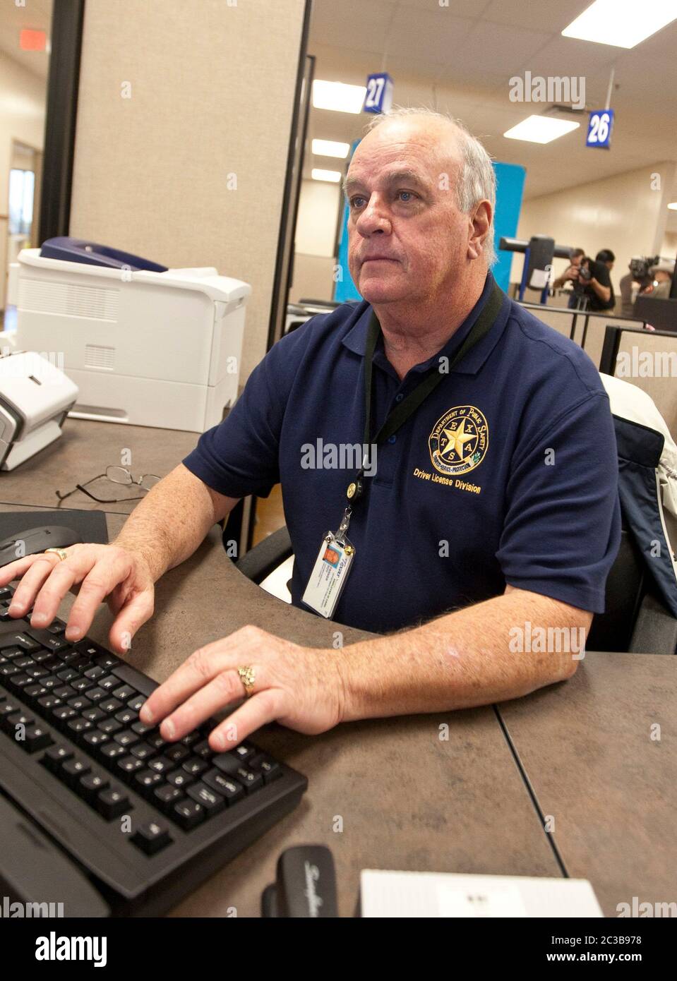 Pflugerville, Texas USA, October 2012: Employee wears a polo-style shirt emblazoned with the Texas state seal while working at the new Texas Department of Public Safety mega driver's license center.  ©MKC / Daemmrich Photos Stock Photo