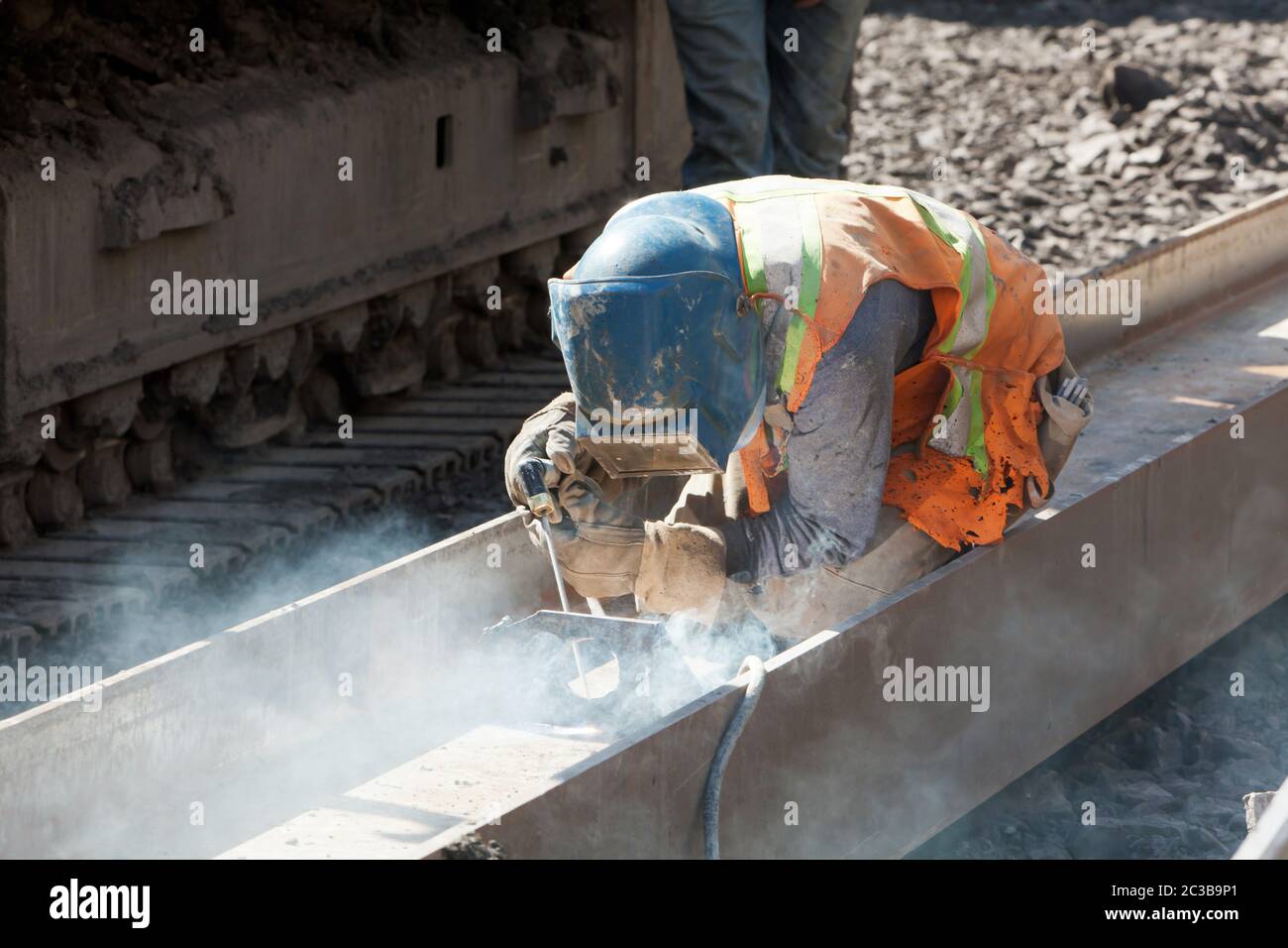 Construction worker welding on a steel I beam wearing full safety ...