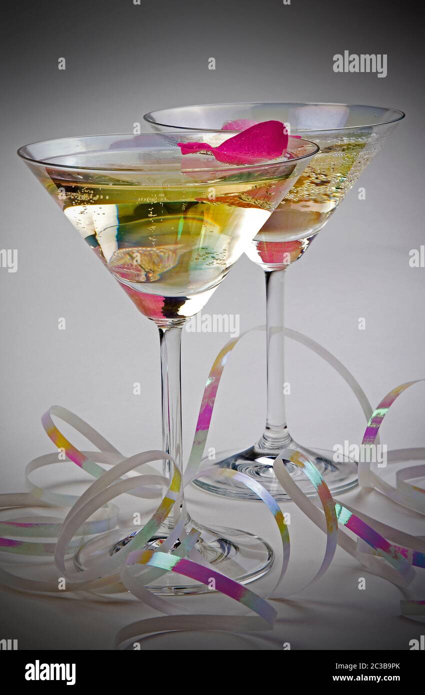 Champagne in glasses with rose petals on plain background with ribbon Stock Photo