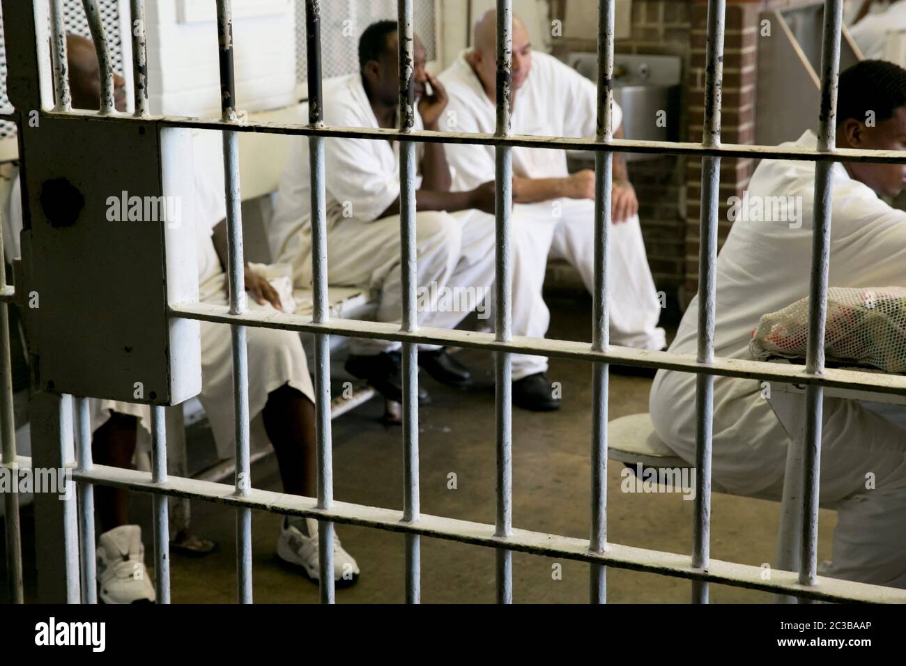Rosharon Texas USA, August 26 2013: Inmates wearing white uniforms gather behind bars in common area where they are allowed to socialize. They are incarcerated in Darrington Prison, a maximum-security unit of the Texas Department of Criminal Justice. ©Marjorie Kamys Cotera/Daemmrich Photography Stock Photo
